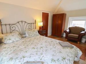 a bedroom with a large bed and a chair at 6 bed Cozy Victorian Cottage in Balnamore