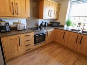 a kitchen with wooden cabinets and a sink at 6 bed Cozy Victorian Cottage in Balnamore +11 photos