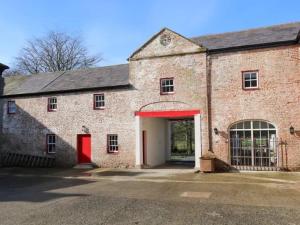 an old brick building with a red door at 6 bed Cozy Victorian Cottage in Balnamore