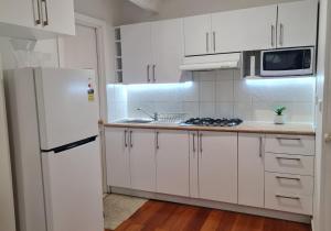 cocina con armarios blancos y nevera blanca en Cosy room close to Melb Airport, en Melbourne