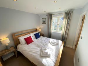 Schlafzimmer mit einem Bett mit weißer Bettwäsche und roten Kissen in der Unterkunft Trewhiddle Villa 29 in St Austell