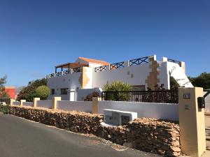 a white house with a stone wall next to a street at Casa Del Medio in Antigua