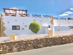 a white building with a stone wall and a tree at Casa Del Medio in Antigua