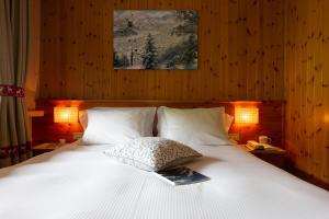 Una cama con sábanas blancas y una almohada. en Hotel Funivia, en Bormio