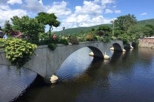 a bridge over a river with people walking on it at Blooming Inn Shelburne Falls in Shelburne Falls