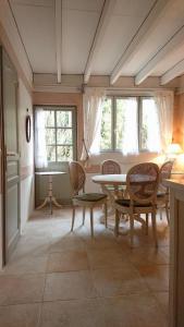 um quarto com uma mesa, cadeiras e janelas em A l'Ombre du Tilleul em Giverny