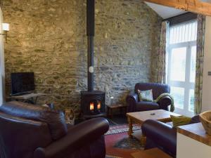 a living room with a stone wall and a wood stove at Ravens Roost in Mathry