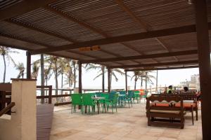 a patio with green chairs and tables on the beach at G2 Beach Hotel in Aquiraz