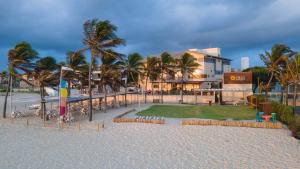 a resort on the beach with chairs and palm trees at Milos Beach Hotel in Aquiraz