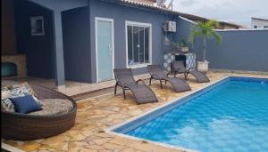 a swimming pool with chairs next to a house at Pousada Litorânea in Saquarema