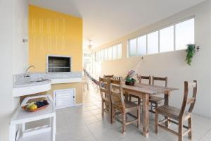 eine Küche und ein Esszimmer mit einem Holztisch und Stühlen in der Unterkunft Embaúba House Casa de Praia, Praia Particular. in Florianópolis