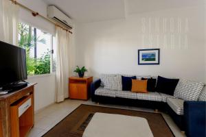 ein Wohnzimmer mit einem Sofa und einem TV in der Unterkunft Embaúba House Casa de Praia, Praia Particular. in Florianópolis