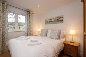 a bedroom with a bed with white sheets and a window at Trewhiddle Retreat V24 by Together Travel - Luxury 4-Bedroom Villa in St Austell
