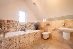 a bathroom with a tub and a toilet and a sink at Trewhiddle Retreat V24 by Together Travel - Luxury 4-Bedroom Villa in St Austell +26 photos