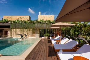 a pool with chairs and umbrellas next to a building at Elcielo Hotel & Restaurant in Medellín