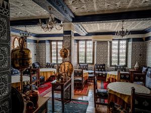 un comedor con mesas, sillas y ventanas en Hôtel LAKASBAH Ait Ben Haddou, en Aït Ben Haddou