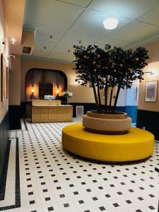 a lobby with a tree in a yellow and white floor at Hôtel De Londres in Menton