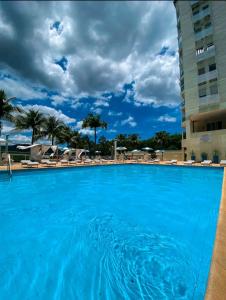 尼泰羅伊的住宿－Apart Hotel Alecrim Praia de Camboinhas com Marina pe na areia，一个带椅子和遮阳伞的大型蓝色游泳池