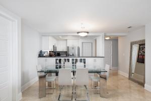 une salle à manger avec une table en verre et des armoires blanches dans l'établissement Ritz Carlton Coconut Grove Luxury 2 BR Apt apts, à Miami