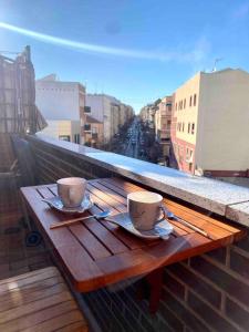 two coffee cups on a wooden table on a balcony at MyHouseSpain - Precioso Ático con gran terraza centro Usera in Madrid