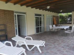 un patio con bancos blancos, mesa y sillas en Casa en Vistalba (Luján de Cuyo)- Mendoza en Vistalba