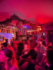 uma multidão num bar com luzes vermelhas em Chamos Hostel Cultural em Arraial do Cabo