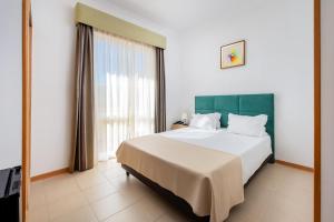 a bedroom with a large bed and a large window at Hotel Santa Catarina Algarve in Portimão