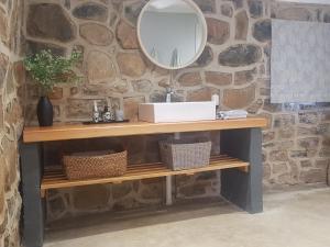 a bathroom with a sink and a mirror on a stone wall at The Stone Barn in Underberg
