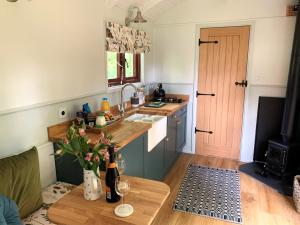 a kitchen with a table and a sink and a stove at Lilliput - Delightful 1-bedroom shepherd's hut in Holsworthy