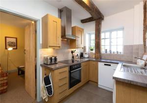 a kitchen with wooden cabinets and white appliances at Corve Cottage Historic cottage in beautiful ludlow in Ludlow