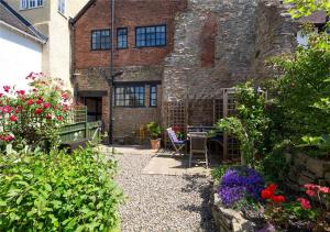 a garden in front of a brick building with flowers at Corve Cottage Historic cottage in beautiful ludlow in Ludlow