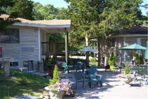 eine Terrasse mit Stühlen und Sonnenschirmen neben einem Haus in der Unterkunft Cedar Park Inn in North Stonington