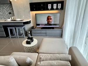 a living room with a tv with a man on the screen at Kamala Beach P72 Exclusive Junior Suite in Bang Tao Beach +107 photos