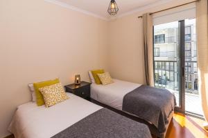 two beds in a room with a window at Acacia Apartment by Atlântica in Funchal