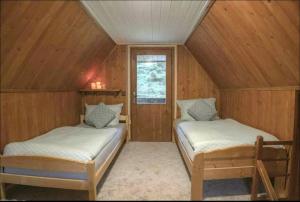 2 camas en una habitación con paredes de madera en Charming cottage KLARA with Sauna, Nature&Privacy near Prague, en Malé Kyšice