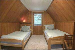 two beds in a room with wooden walls at Charming cottage KLARA with Sauna, Nature&Privacy near Prague in Malé Kyšice