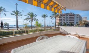 a balcony with a table and chairs and palm trees at R139 Beachfront apartment Guillem in Calafell