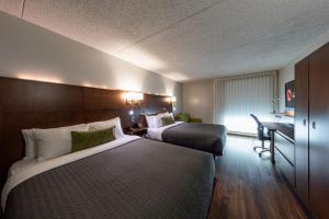 um quarto de hotel com duas camas e uma secretária em Hôtel & Suites Normandin Québec em Cidade de Quebec