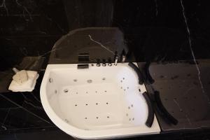 uma banheira branca num quarto com azulejos pretos em Grand hotel irpinia & Family SPA em Avellino