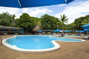 una grande piscina con ombrelloni e tavoli blu di Hotel Guadaira Resort a Melgar