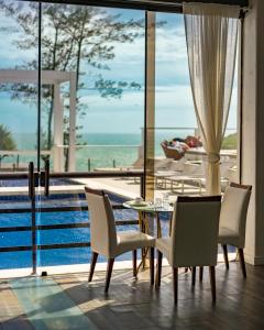 uma sala de jantar com mesa e cadeiras e uma piscina em Greco Hotel em Búzios