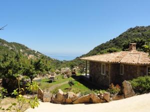 CORSACASA Villa in Palombaggia sea view في بورتو فيكيو: منزل على الشاطئ مع جبال في الخلفية