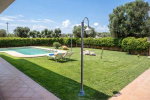 a lamp post in a yard with a swimming pool at Ellea Resort in San Michele Salentino