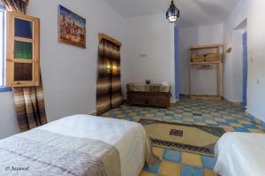 舍夫沙萬的住宿－Dar El Fanne，一间带两张床的卧室,铺有瓷砖地板。