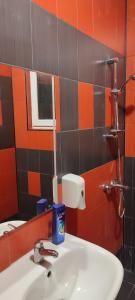 y baño con lavabo y azulejos de color naranja y negro. en Ivka en Gabrovo
