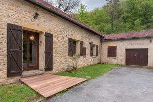 ceglany budynek z drewnianą rampą obok garażu w obiekcie Maison de vacances avec piscine w mieście Montignac