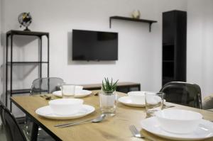 a wooden table with plates and glasses and a television at Fantastic apartment in the heart of Alicante in Alicante
