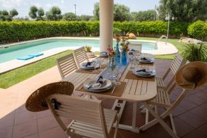 uma mesa de madeira e cadeiras ao lado de uma piscina em Ellea Resort em San Michele Salentino