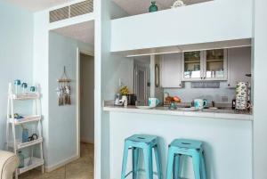 a kitchen with a counter and two blue stools at Beachfront Sunrise  in Galveston