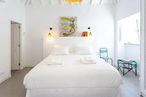 a white bedroom with a large bed with white sheets at Casa da Tavira in Tavira